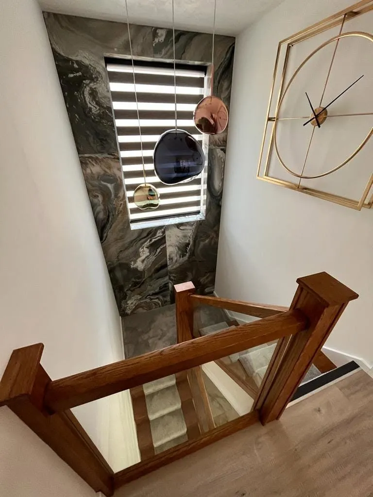 Feature staircase with marble wall tiles and glass balustrade by AG Joinery