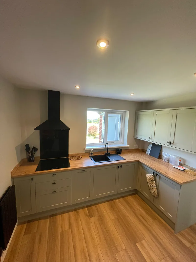 Sage green shaker kitchen with solid oak worktops, black chimney extractor and induction hob by AG Joinery Lancashire